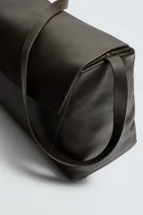 Bolso tipo bandolera de gran tamaño fabricado en piel con acabado grabado. Cuenta con un compartimento principal con cierre de solapa magnética y cremallera, además de bolsillos interiores. Incluye un asa de hombro ajustable en piel.