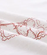 Musculosa blanca de algodón, de corte comfort y cuello redondo. Presenta un estampado localizado en el pecho con un diseño de palmeras y un atardecer en tonos rosados y naranjas.