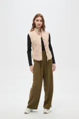 Chaleco negro con diseño capitoneado, cierre frontal con botones a presión y cuello alto.