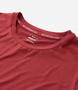 Remera deportiva de hombre en color rojo oscuro, con mangas cortas, cuello redondo y detalle de líneas negras en la manga. Confeccionada en poliéster con tecnología dry fit.