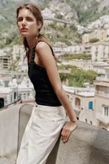 Musculosa de algodón color negro, con escote redondo y tiras anchas. Presenta detalles de encaje negro en los bordes y aplicación de perlas pequeñas alrededor del escote y los hombros.