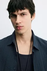 Camisa de corte relajado confeccionada en tejido fluido con textura acanalada. Presenta cuello solapa, manga corta y cierre frontal con botones.