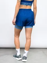 Short deportivo Umbro de color azul con calza interna incorporada. Cuenta con cintura elástica con cordón de ajuste, ribete reflectante y logo de la marca estampado en la pierna.