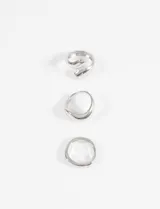 Set de tres anillos de metal plateado con diseño irregular y orgánico.