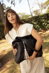 Bolso tipo shopper color rojo, confeccionado en 100% cuero vacuno, con diseño geométrico de paneles y detalle de fleco decorativo colgante.