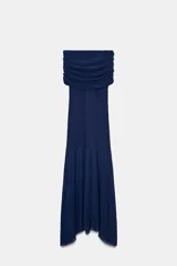 Vestido largo azul marino, sin mangas, con escote recto fruncido tipo *off-shoulder* y falda con bajo asimétrico y semitransparente.