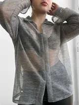 Blusa plateada traslúcida con cuello camisero y mangas largas.