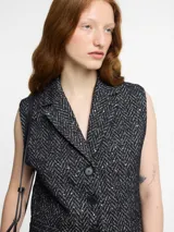 Chaleco sastrero negro con solapa y botones en la parte delantera. Textura con bordados metálicos.