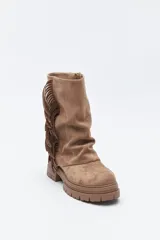 Bota de caña media con flecos laterales, confeccionada en material con textura tipo gamuza. Presenta una silueta relajada y suela robusta con base dentada.