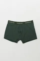 Boxer de algodón color verde oscuro con elástico blanco que lleva la palabra "Uniform" repetida en letras blancas.