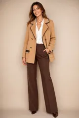 Blazer cruzado color beige, con cierre de botones, bolsillos frontales decorados con encaje y perlas colgantes, y aplique artesanal con perla en la solapa.