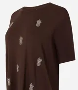 Blusa marrón de mangas cortas, confeccionada en viscosa, con cuello redondo y bordados de piñas en la parte delantera.