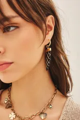 Aro de argolla dorada con dije colgante en forma de cuerno, color negro con patrón de red blanco y detalle dorado en la parte superior.