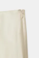 Falda midi de tiro medio, color beige, con detalle de combinación de tejidos a contraste y volante plisado semitransparente en el bajo. Cuenta con cierre lateral de cremallera oculta.