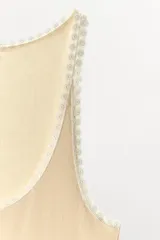 Top sin mangas de tejido rib color beige, con escote redondo y detalle de puntilla a contraste en los bordes.