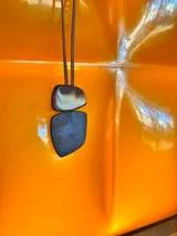 Collar de largo regulable con cordón de cuero y dos piezas colgantes de resina en tonos tierra y marmolados.