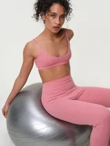 Top deportivo de breteles finos regulables, color rosado, con diseño liso y escote redondo.