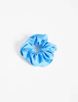 Gomita de pelo tipo scrunchie de tela celeste.