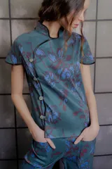 Top de tafeta elastizada con estampado floral, cuello mao con ribete en contraste, mangas cortas y cierre frontal cruzado con botones a la vista.