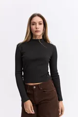 Polera de manga larga con cuello alto, confeccionada en tejido de algodón con textura acanalada y calce ajustado al cuerpo.