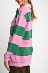 Sweater tipo polo de manga larga con diseño de rayas horizontales anchas en color rosa y gris. Presenta cuello camisero con cierre frontal de botones y puños elásticos.