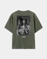 Remera oversize verde militar con efecto acid wash, corte amplio y manga corta. En la espalda presenta una estampa en blanco y negro con la forma de una estampilla postal que muestra a Joey Ramone sosteniendo un gato, acompañada por el texto "KABOA INDUSTRIES".