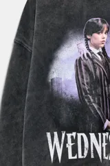 Buzo de cuello redondo con efecto lavado, manga larga y puños en rib. Presenta una estampa frontal de la serie Wednesday con acabado desgastado.