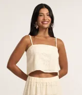 Blusa cropped de algodón color marfil, con escote recto, tirantes finos ajustables y estampa con diseño de guipire floral.