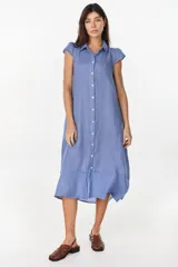Vestido midi color azul de lino italiano, con diseño camisero, cuello camisero, mangas cortas abullonadas, cierre frontal con botones y bolsillos laterales.