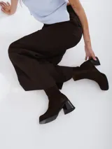 Bota de caña media con punta cuadrada, confeccionada en cuero gamuzado color marrón, con taco bloque y suela de goma negra.