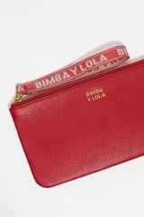 Monedero grande de piel vacuna color rojo, con cierre superior y correa de muñeca de tela con el logo de la marca. Incluye el logo metálico dorado en el frente.