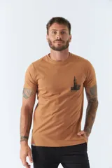 Remera color caramelo de corte clásico, con cuello redondo y manga corta. Estampa pequeña en el pecho con el dibujo de un edificio y la inscripción "BROOKSFIELD".