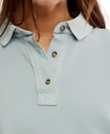 Remera estilo polo blanca de corte amplio con cuello clásico y botonadura corta en el frente. Tiene mangas cortas con dobladillo y aberturas laterales en el ruedo.