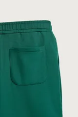 Pantalón jogger de corte relajado y pernera ancha, confeccionado en tejido de algodón con interior perchado. Cuenta con cintura elástica ajustable mediante cordón interior, bolsillos laterales y un bolsillo trasero de plastrón.