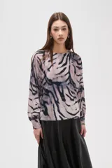 Blusa de manga larga con estampado animal print abstracto en tonos grisáceos y negros. Presenta cuello a la base y cierre con botón en la parte posterior.