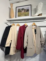 Blazer de corte sastre en color gris claro, con solapas clásicas, bolsillos frontales con solapa y mangas con detalle de frunce.