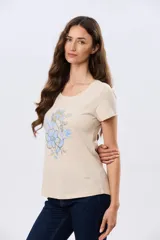Remera beige de manga corta con cuello redondo, confeccionada en algodón con un diseño delantero que combina estampa floral y detalles bordados.