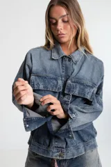 Campera de denim azul con calce boxy, cuello clásico, cierre con botones metálicos, mangas largas con puños abotonados, dos bolsillos frontales con solapa y parche con logo en el frente.