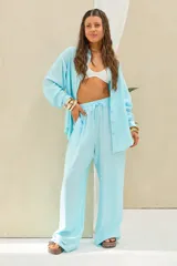 Pantalón celeste de corte holgado y pernera ancha, con cintura elástica fruncida y cordón ajustable del mismo tono.