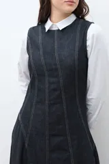 Maxi vestido sin mangas de denim oscuro, con corte al cuerpo en el torso y falda acampanada que cae hasta el tobillo. Presenta costuras visibles en contraste que definen los paneles del vestido.