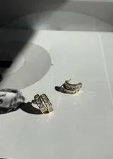 Par de aros tipo argolla dorados con incrustaciones de zirconias blancas. Cierre tipo mariposa y aguja de plata 925.
