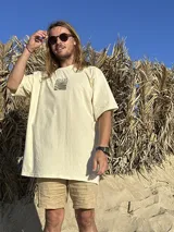 Remera color crema de algodón con estampa en la espalda de un paisaje playero con el texto "Chema Sure Chate et la mer".