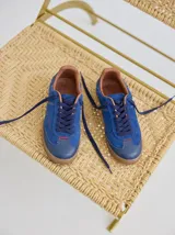 Championes de cuero color azul, con detalles en gamuza y pespuntes rojos. Tienen suela de goma texturizada y cordones azules.