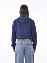 Campera tipo hoodie cropped de color azul marino, con cierre frontal completo, capucha y mangas largas con puños elásticos.