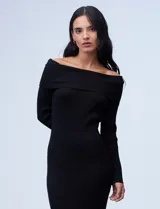 Vestido midi tejido en punto rib color negro, con escote bote y cuello volcado. Terminación de ruedo lateral con tajo y mangas largas. Marca Absolutely Famous.