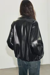 Chaqueta bomber de efecto piel con cuello solapa, cierre frontal de cremallera metálica, bolsillos laterales de vivo y bajo y puños con elástico.