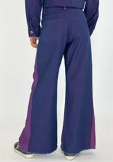 Pantalón de denim gris oscuro con paneles laterales en color bordó y corte acampanado.