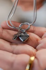 Pulsera de cadena tipo serpiente en color plateado, con dijes colgantes de dos cruces y un corazón grabado con la palabra 'MUM'.