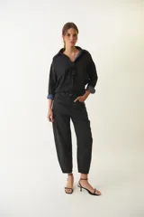 Pantalón jean slouchy negro de tiro medio, con silueta relajada, bolsillos laterales y traseros, y leve entalle en los tobillos.