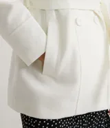 Campera alargada de polivelour color blanco, con cuello alto que se pliega y se ata a la cintura, mangas largas, abotonado frontal doble, bolsillos y cinturón.